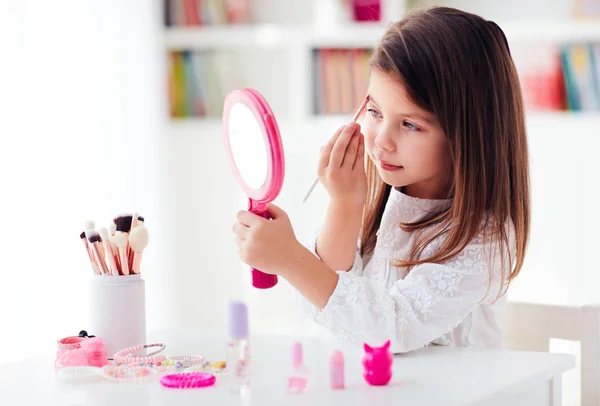 Mooi jong meisje, kid toepassen van make-up met borstel en zakspiegel — Stockfoto