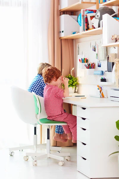 Lindos niños felices están sentados juntos y dibujando en el escritorio en casa —  Fotos de Stock