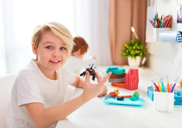 Niños felices están creando las artesanías de modelado de plastilina en la habitación de los niños —  Fotos de Stock