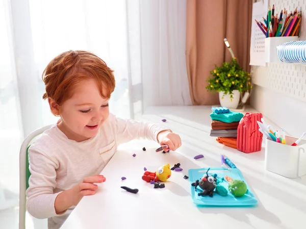 快乐的孩子正在用儿童房桌上的塑料模型制作手工工艺品 — 图库照片