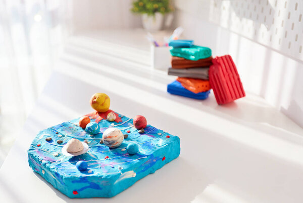 handcrafted solar system made of plasticine by kids, on the desk in the kids room, school project