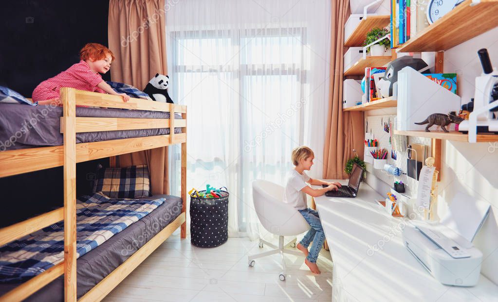 two boys, brothers in kids room with bunk bed and wall shelves