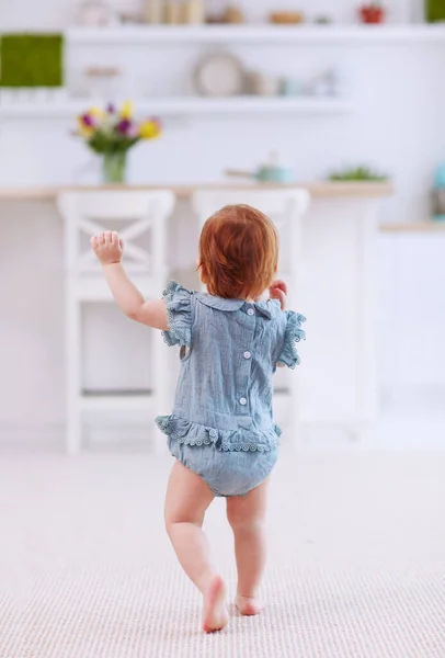 Primeros pasos de linda niña en traje de cuerpo alejándose, en la alfombra en casa —  Fotos de Stock