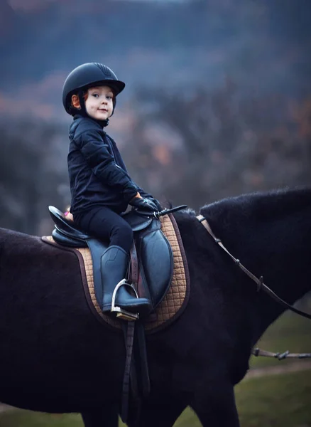 Niño, niño jinete se queda con confianza durante el paseo a caballo — Foto de Stock