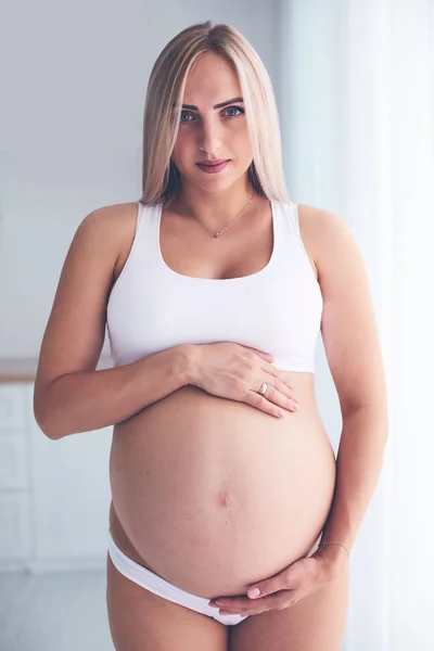 Pregnant woman embracing her belly, enjoying new condition — Stock Photo, Image