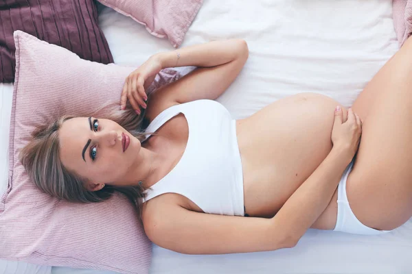 Молодая беременная женщина отдыхает в постели утром — стоковое фото