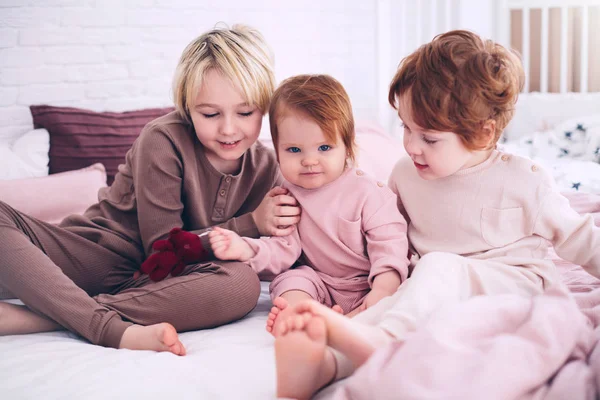 Cute happy kids, siblings sitting together on the bed in the morning, in pajamas — Stock Photo, Image