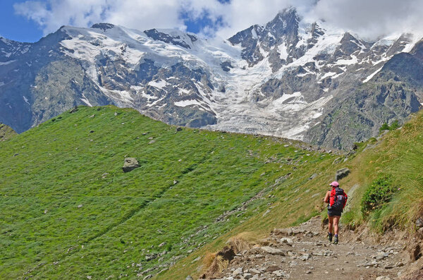 girl hiker looking out over moraine covered glacier in mountains