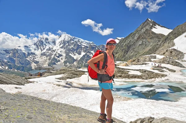 苗条的女孩徒步旅行者高在意大利阿尔卑斯山以上的冰覆盖湖 并与蒙特卡洛在背景下 — 图库照片