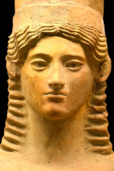Ancient Greek Sculpture of a woman\'s head with long wavy hair and a piercing gaze. Dated to 600BC