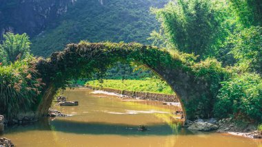 Taş ve kayalardan yapılmış eski romantik bir köprü, yaz boyunca küçük nehri geçer, güzel yerlere, Çin 'in kırsal ve doğa bölgelerine seyahat eder.