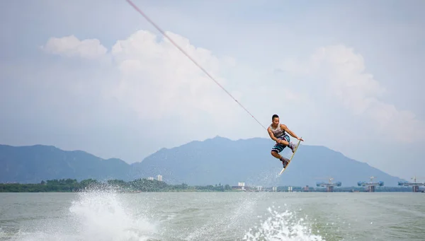 Young Asian man wakeboarding on a river in China, extreme sports, adventure lifestyle, summer vacation, hobby and lifestyle