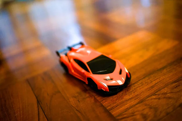 Small Orange Speed Toy Car Dark Wooden Brown Parquet Childhood — Stock Photo, Image