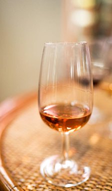 Ahşap masanın üzerinde bir kadeh şarap, arka planda bulanık.