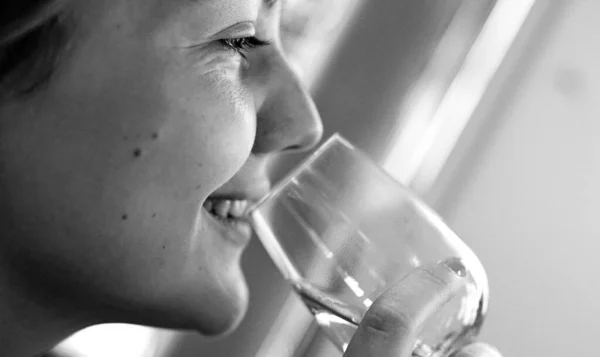 Blurred closed up view beautiful happy Caucasian girl is drinking a glass of white wine, film noise black and white photography, tasting alcoholic drinks concept, copy past text