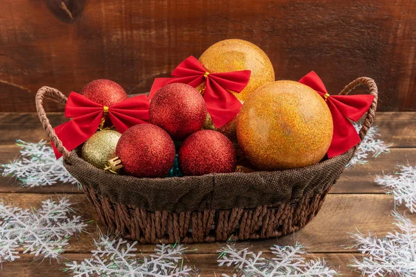 Christmas decorations lie in a basket. Basket stands on a wooden table.