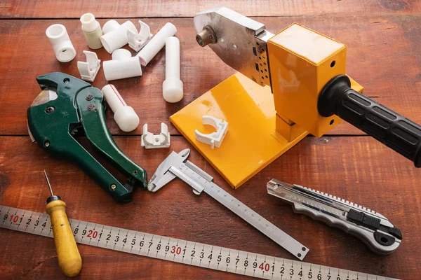 Equipment for welding and cutting plastic pipes on a wooden background.