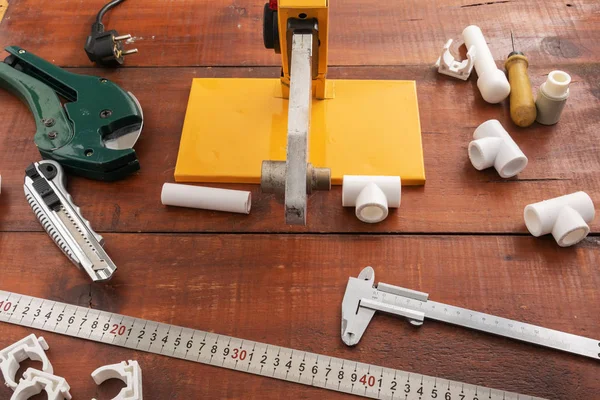 Equipment for welding and cutting plastic pipes on a wooden background.