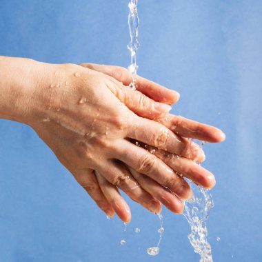 Mavi arka planda bir kadın eli. Ellerine bir su akıntısı düşüyor..