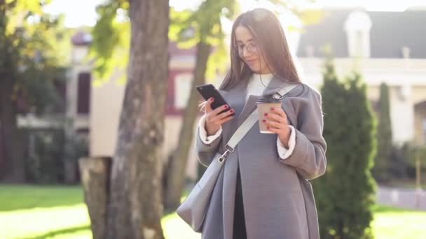 Mujer joven enviando mensajes de texto o usando teléfono inteligente — Vídeos de Stock