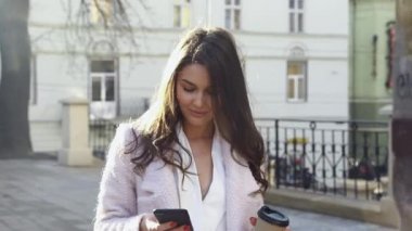 Sokakta dikilirken akıllı telefonuna mesajlar yazan çekici bir kadın. Dışarıda eğlenmek ve eğlenmek. Kameranın önünde akıllı telefonlu güzel bir esmer. Güzel kız.
