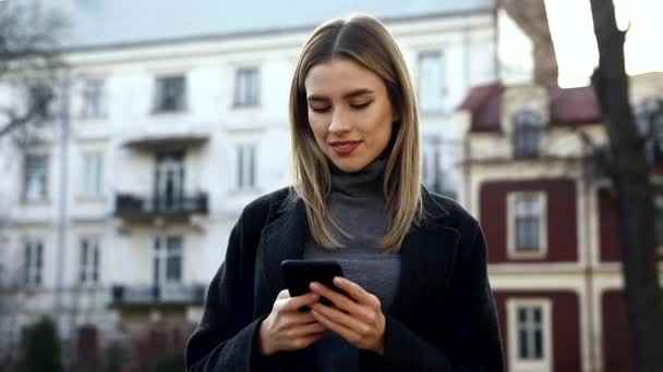 Femme Attirante Tapant Des Messages Sur Son Smartphone Tout Promenant — Video