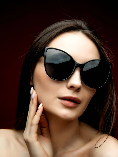 Mannequin en lunettes de soleil, belle jeune femme. plan lstudio, fond rouge — Photo