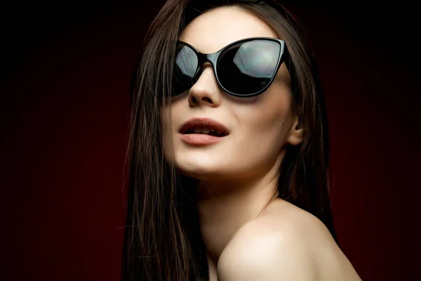 Mannequin en lunettes de soleil, belle jeune femme. plan lstudio, fond rouge — Photo
