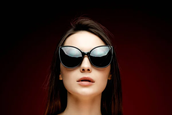 Retrato de joven hermosa mujer delgada en vestido sexy con labios sensuales en el estudio con gafas de sol sonriendo y posando Imagen de archivo