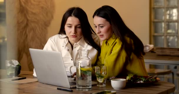 Две Брюнетки Одетые Повседневную Одежду Смотрят Смешные Видео Ноутбуке Сидя — стоковое видео