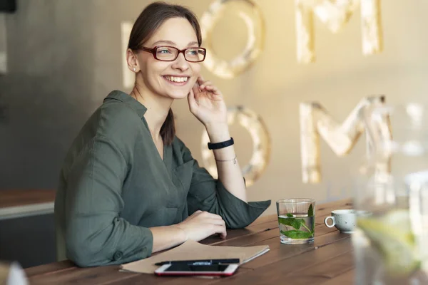 一个穿着时髦眼镜的漂亮年轻女子对着相机微笑的镜头 背景风格的咖啡屋 — 图库照片