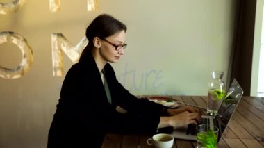 Şık gözlüklü, odaklanmış iş kadını laptopta çalışan, kafeye odaklanmış, kafeteryada bilgisayar ve kapuçinoyla çalışan, serbest çalışan, online okuyan, internette gezinen, faturaları kontrol eden,