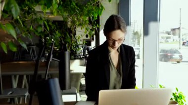 Şık gözlüklü, odaklanmış iş kadını laptopta çalışan, kafeye odaklanmış, kafeteryada bilgisayar ve kapuçinoyla çalışan, serbest çalışan, online okuyan, internette gezinen, faturaları kontrol eden,