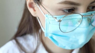 Gözlüklü, sağlık hizmetleri uzmanı bir kadının hastanede ameliyat maskesi takarken ön görüntüsü. Coronavirus 'taki sağlık çalışanları Covid19 salgını