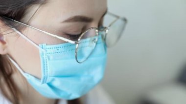 Gözlüklü, sağlık hizmetleri uzmanı bir kadının hastanede ameliyat maskesi takarken ön görüntüsü. Coronavirus 'taki sağlık çalışanları Covid19 salgını
