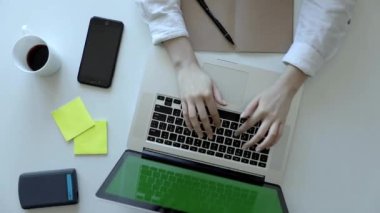 Kadın elleri klavye bilgisayarında daktilo kullanıyor. Üst görünüm. Modern akıllı telefon. Sanat masasında çalışıyor.