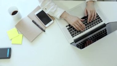 Kadın elleri klavye bilgisayarında daktilo kullanıyor. Üst görünüm. Modern akıllı telefon. Sanat masasında çalışıyor.