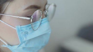 Gözlüklü, sağlık hizmetleri uzmanı bir kadının hastanede ameliyat maskesi takarken ön görüntüsü. Coronavirus 'taki sağlık çalışanları Covid19 salgını