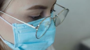 Gözlüklü, sağlık hizmetleri uzmanı bir kadının hastanede ameliyat maskesi takarken ön görüntüsü. Coronavirus 'taki sağlık çalışanları Covid19 salgını