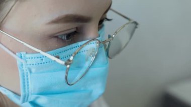 Gözlüklü, sağlık hizmetleri uzmanı bir kadının hastanede ameliyat maskesi takarken ön görüntüsü. Coronavirus 'taki sağlık çalışanları Covid19 salgını