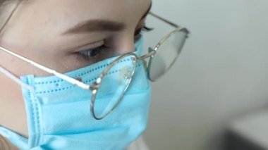 Gözlüklü, sağlık hizmetleri uzmanı bir kadının hastanede ameliyat maskesi takarken ön görüntüsü. Coronavirus 'taki sağlık çalışanları Covid19 salgını