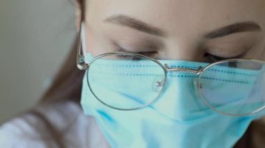 Gözlüklü, sağlık hizmetleri uzmanı bir kadının hastanede ameliyat maskesi takarken ön görüntüsü. Coronavirus 'taki sağlık çalışanları Covid19 salgını
