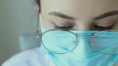 Gözlüklü, sağlık hizmetleri uzmanı bir kadının hastanede ameliyat maskesi takarken ön görüntüsü. Coronavirus 'taki sağlık çalışanları Covid19 salgını