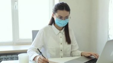 25-26 yaşlarındaki Avrupalı iş kadınları PM2.5 ve virüsü korumak için ofiste çalışırken koruyucu maske takıyorlar. Sağlık ve Koruma Konsepti.