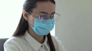 25-26 yaşlarındaki Avrupalı iş kadınları PM2.5 ve virüsü korumak için ofiste çalışırken koruyucu maske takıyorlar. Sağlık ve Koruma Konsepti.