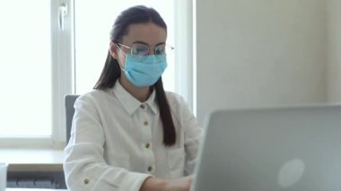 25-26 yaşlarındaki Avrupalı iş kadınları PM2.5 ve virüsü korumak için ofiste çalışırken koruyucu maske takıyorlar. Sağlık ve Koruma Konsepti.