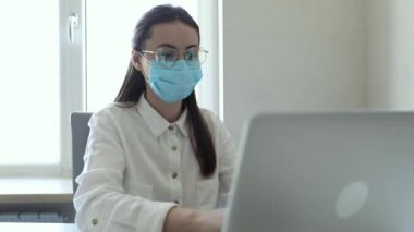 25-26 yaşlarındaki Avrupalı iş kadınları PM2.5 ve virüsü korumak için ofiste çalışırken koruyucu maske takıyorlar. Sağlık ve Koruma Konsepti.