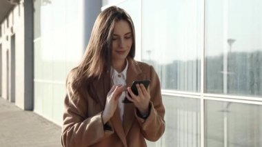 Güzel bir iş kadını akıllı telefon mesajları kullanıyor şirket ofisinde yürüyor cep telefonunda kısa mesajlar yazıyor e-postalarını kontrol ediyor 4k görüntülerinde başarılı kadın yöneticiler.
