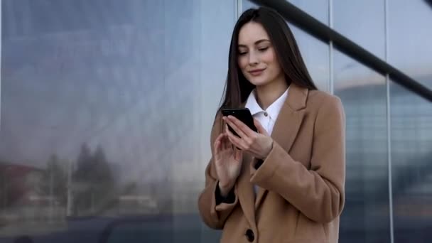 漂亮的女商人用智能手机发短信走进公司办公室用手机打字发短信查邮件成功的女主管在公司工作4K段视频 — 图库视频影像
