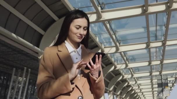 成年白种人自信的年轻商业女性正在现代办公大楼附近使用智能手机应用程序 中低角4K慢速运动公司拍摄与移动相机周围 — 图库视频影像